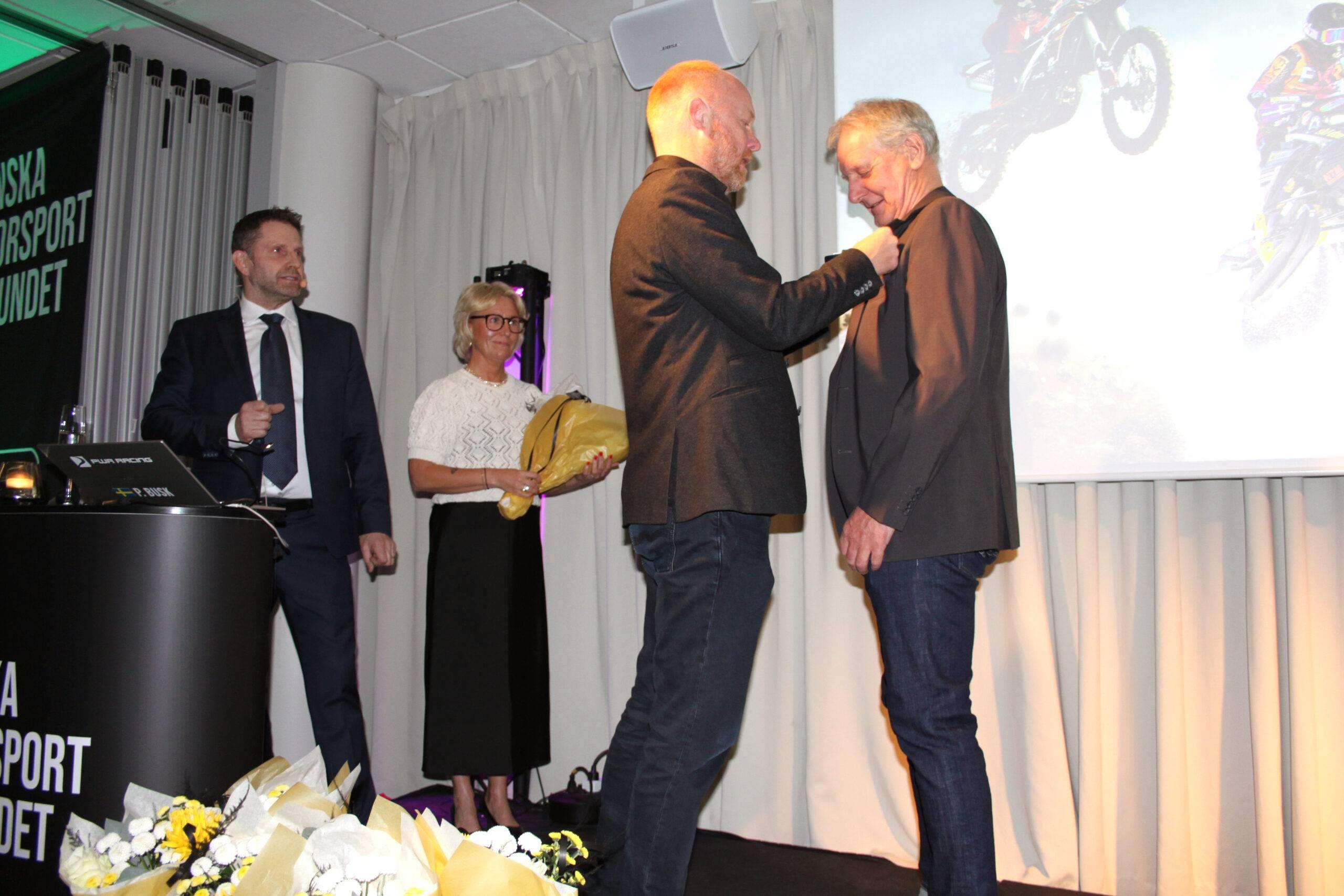 Gunnar tar emot utmärkelsen förtjänstmedalj från Jonas Gustafsson