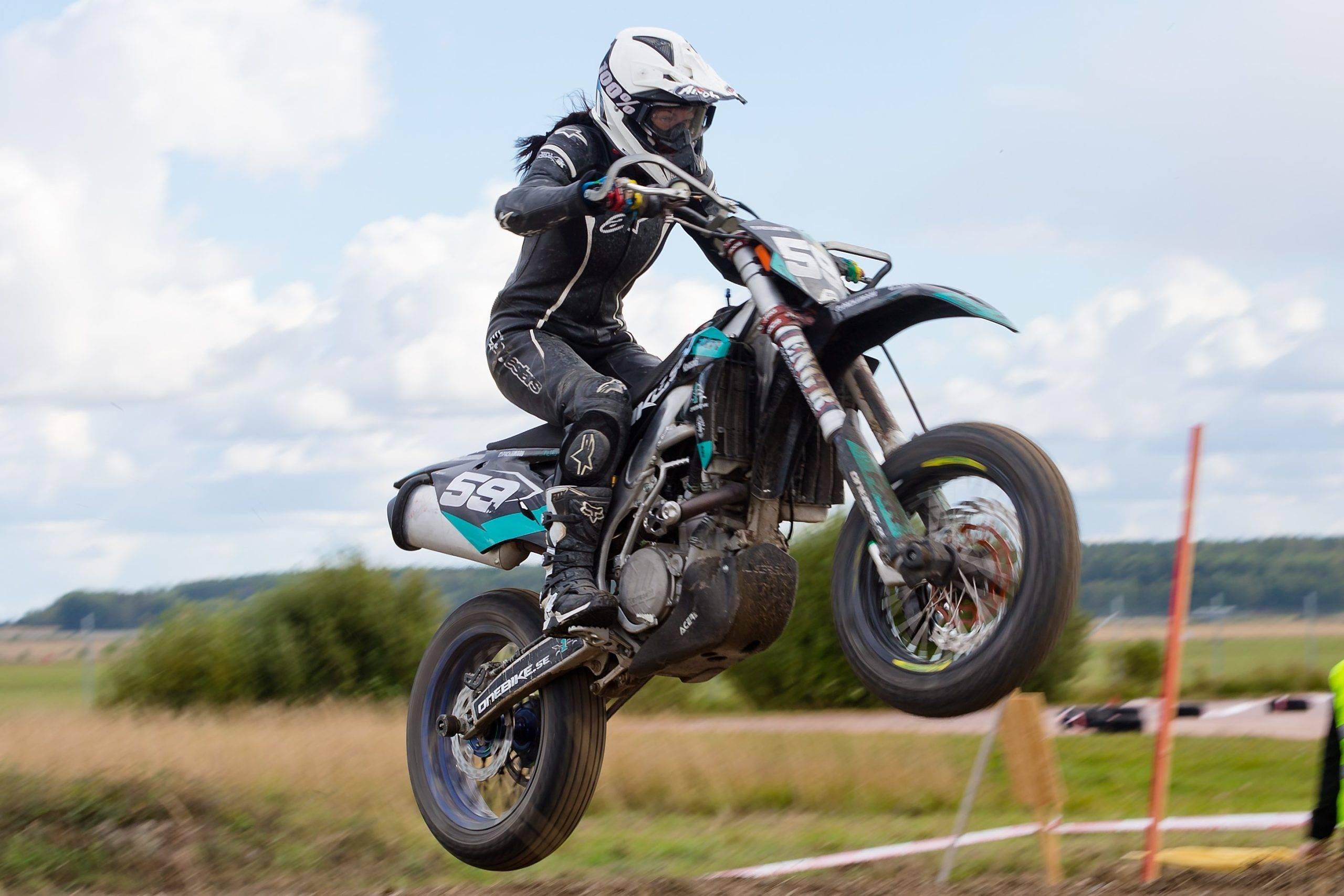 Kvinnlig förare hoppar med motorcykeln i supermoto
