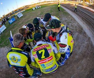 Ett speedwaylag i Bauhausligan står samlade i en tät ring med sina huvuden lutade inåt.