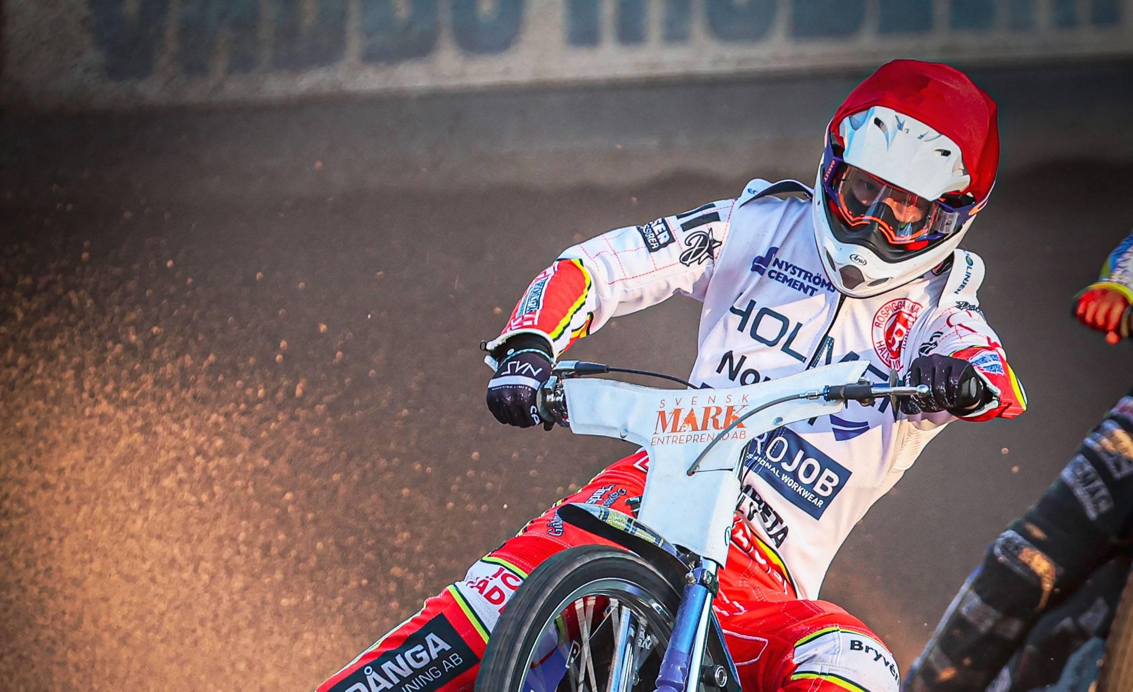 E speedwayförare kör speedway med intensiv blick på banan.