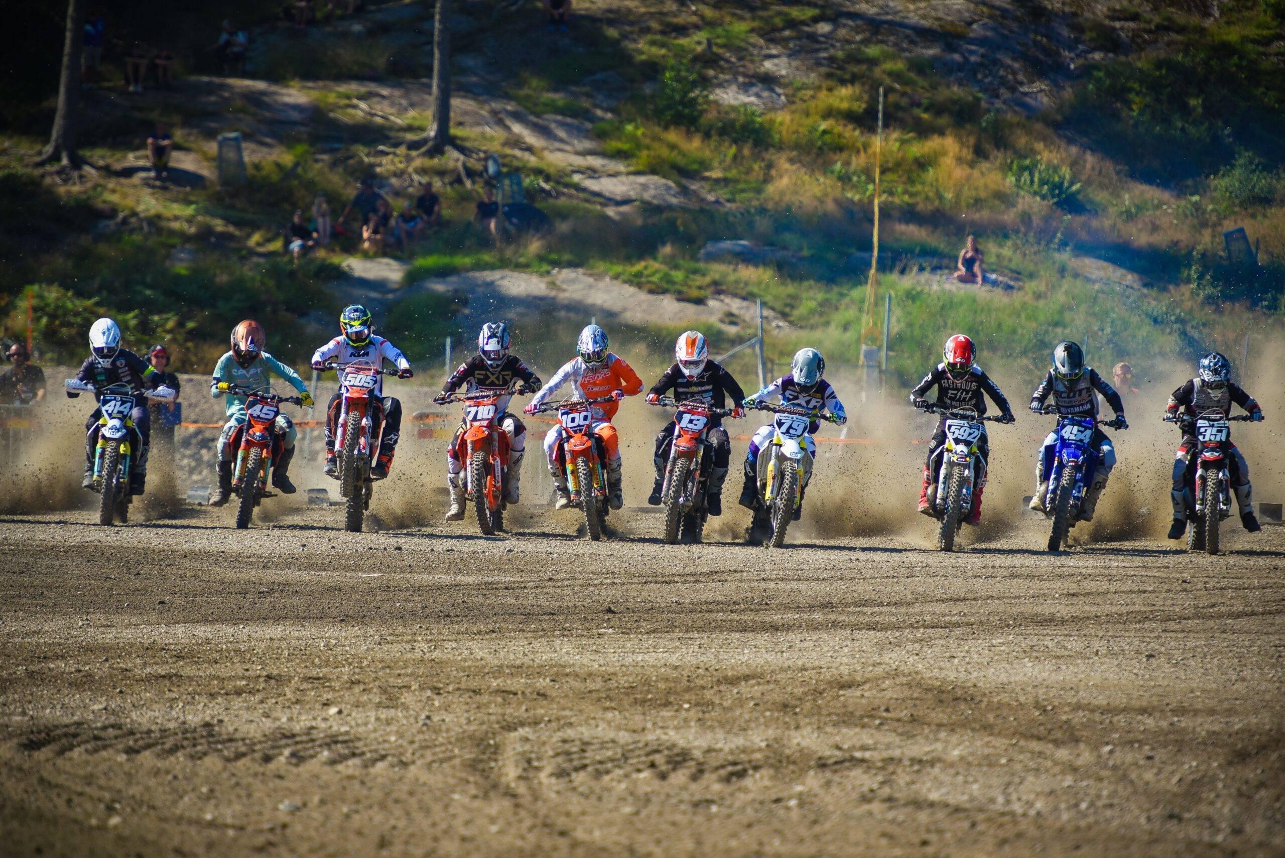 Tio motocrossförare i full fart på startrakan.