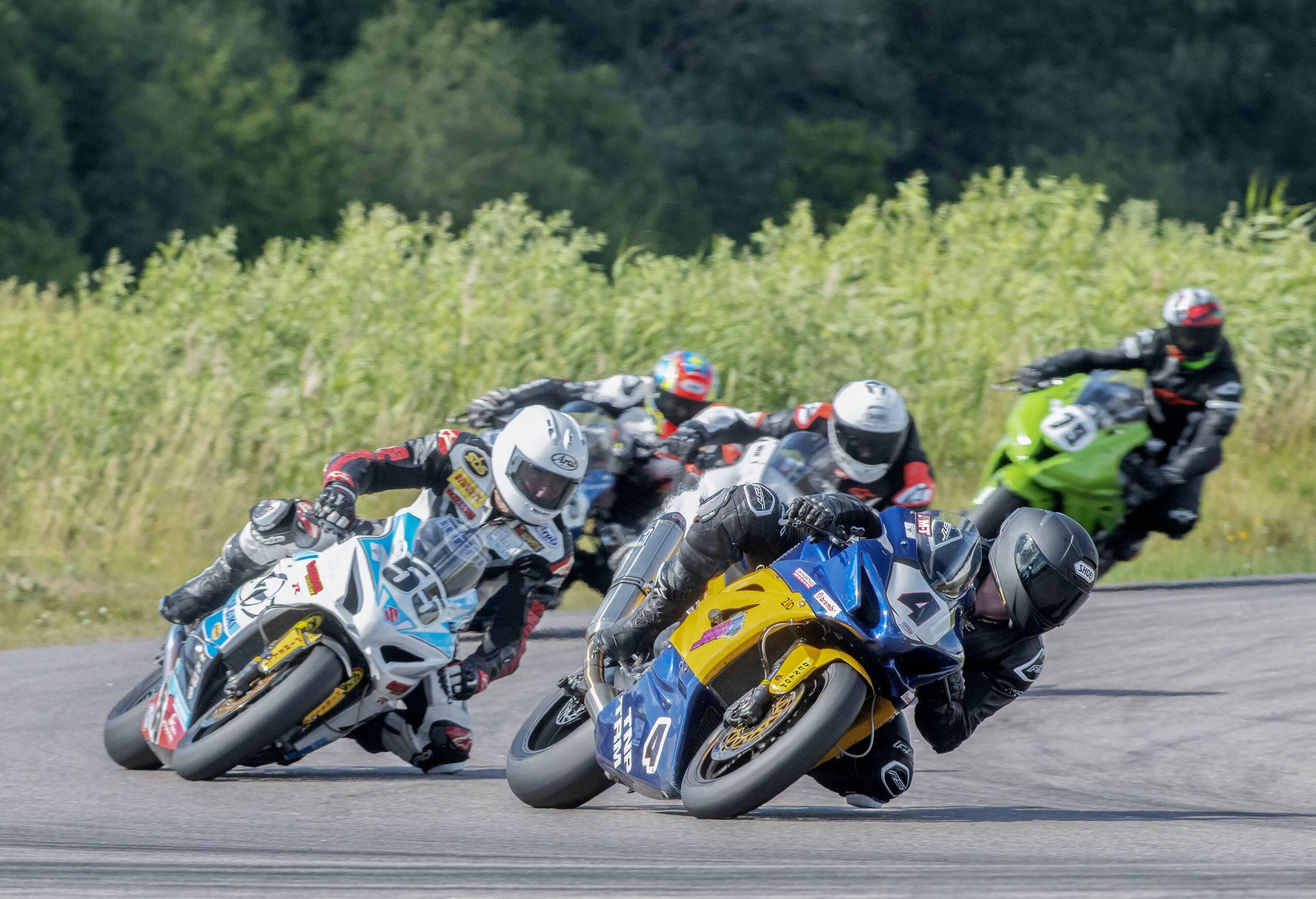 Fem roadracingförare kör ut ur en kurva.