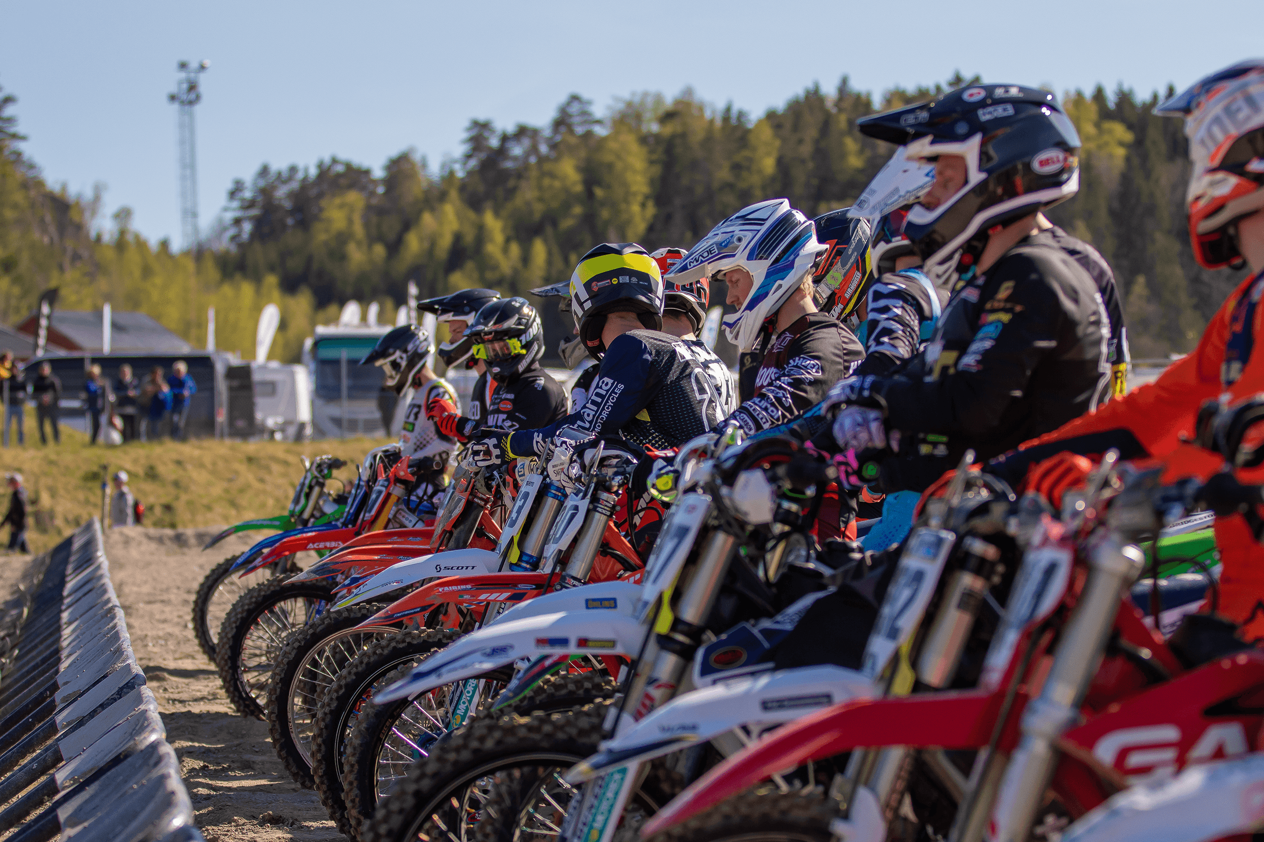 En grupp med motocrossförare står framför startgrindarna och gör sig redo för tävling.