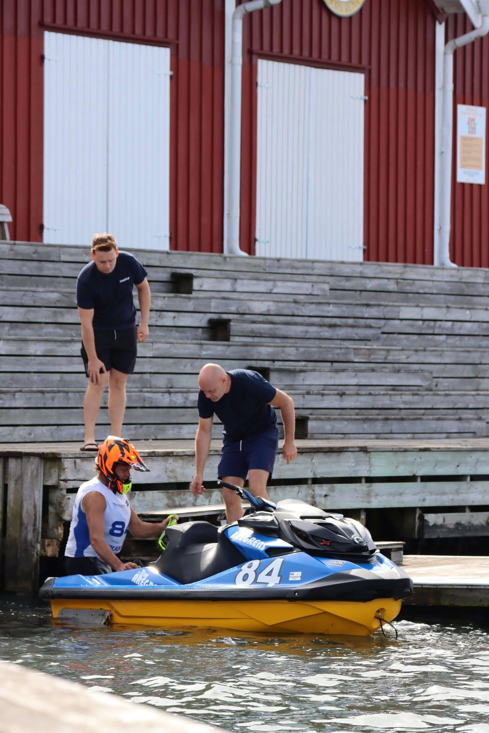 Två personer hjälper stillastående aquabike vid bryggan