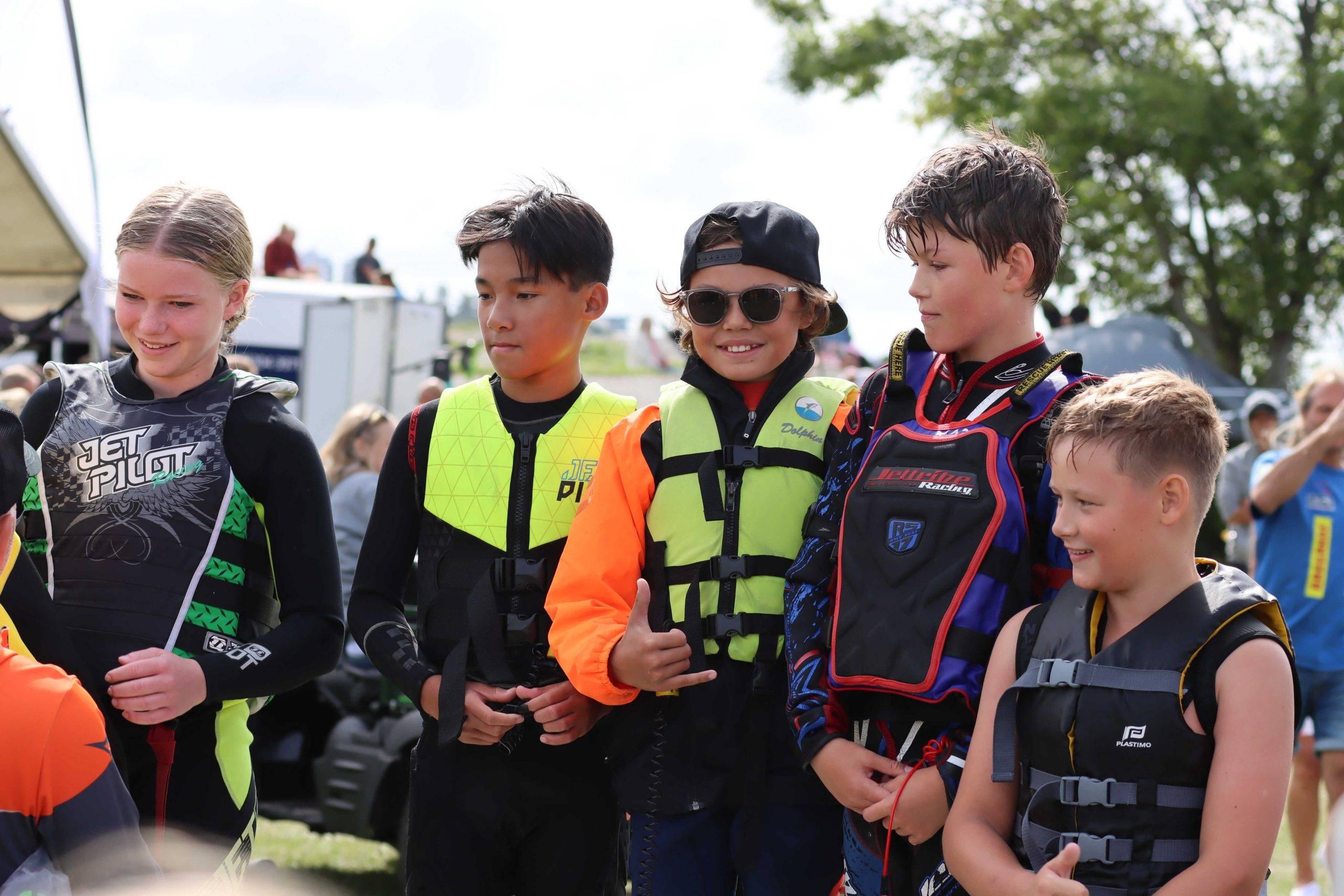 En grupp med ungdomsförare i aquabike ser glada ut i sina flytvästar