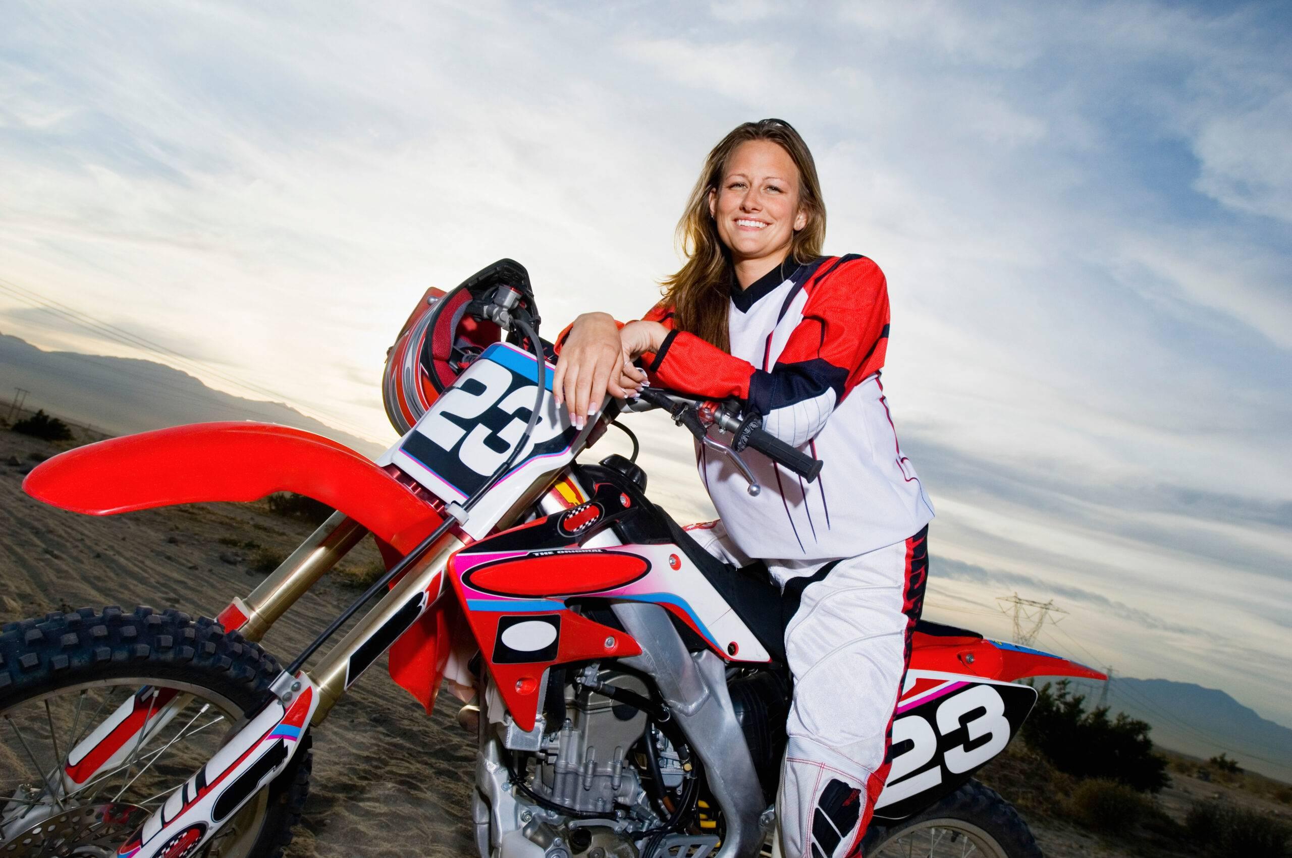 En kvinnlig förare sitter på sin motocross och ler