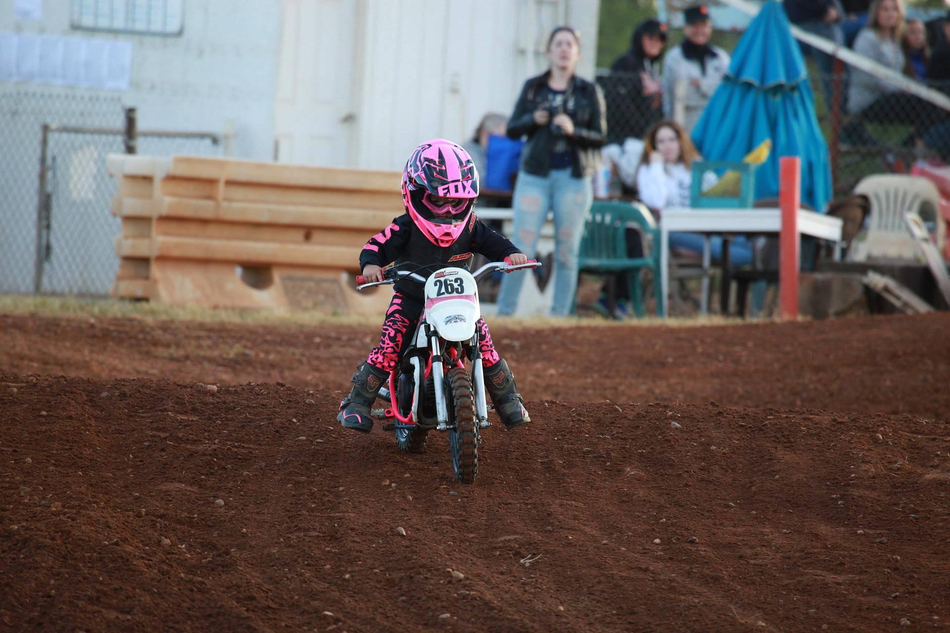 Ett litet barn kör på en liten rosa motocross.