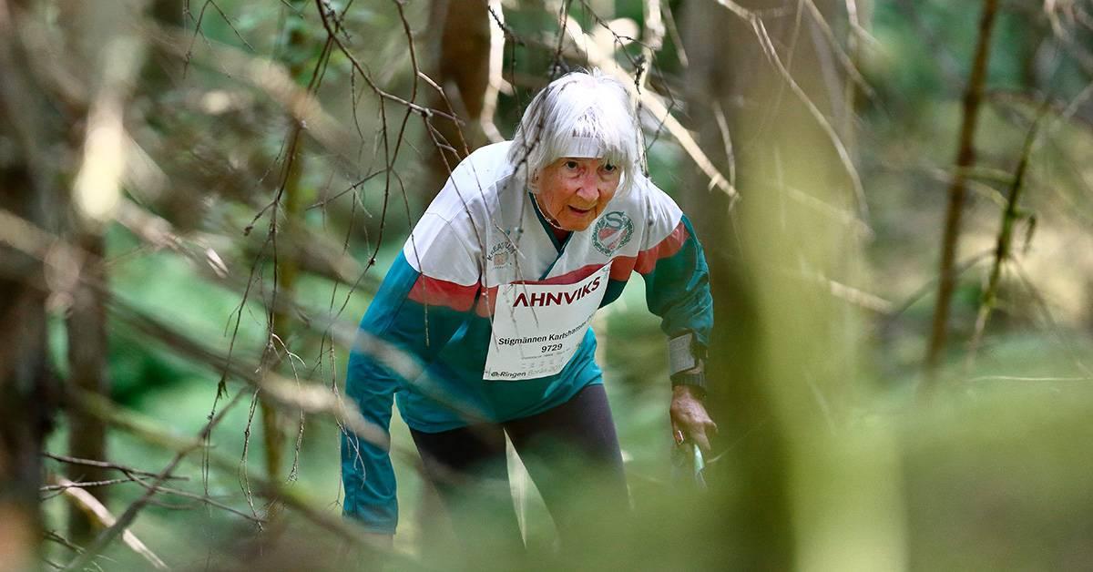 En äldre dam orienterar i skogen.