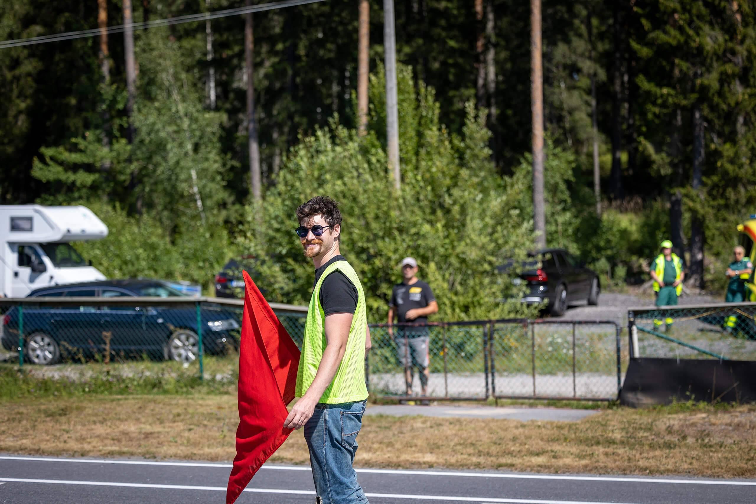 En funktionär på en asfaltsbana tittar leene mot kameran. Fotograf: Maeva Sponbergs