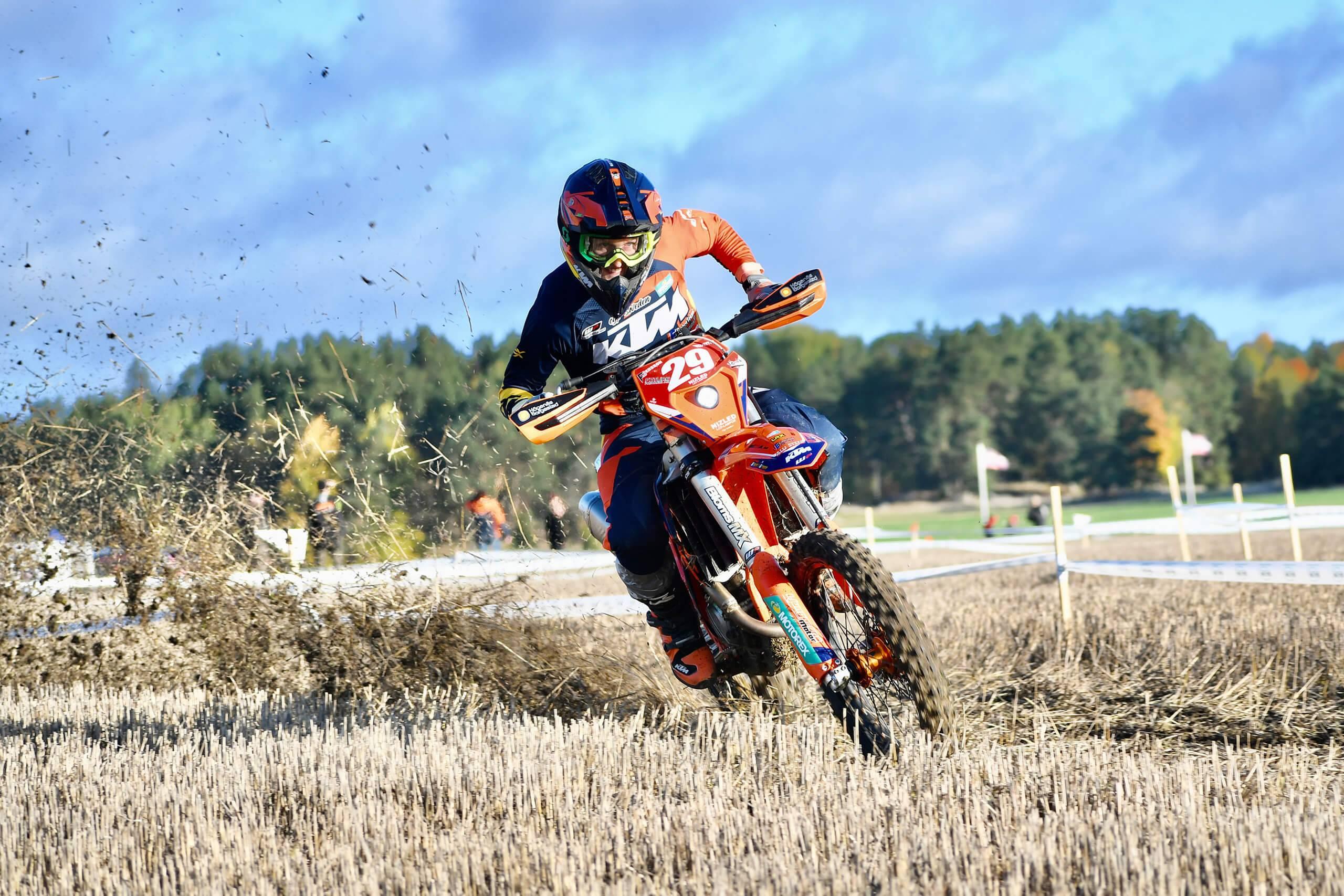 En enduroförare gasar på så att jorden stänker på ett fält