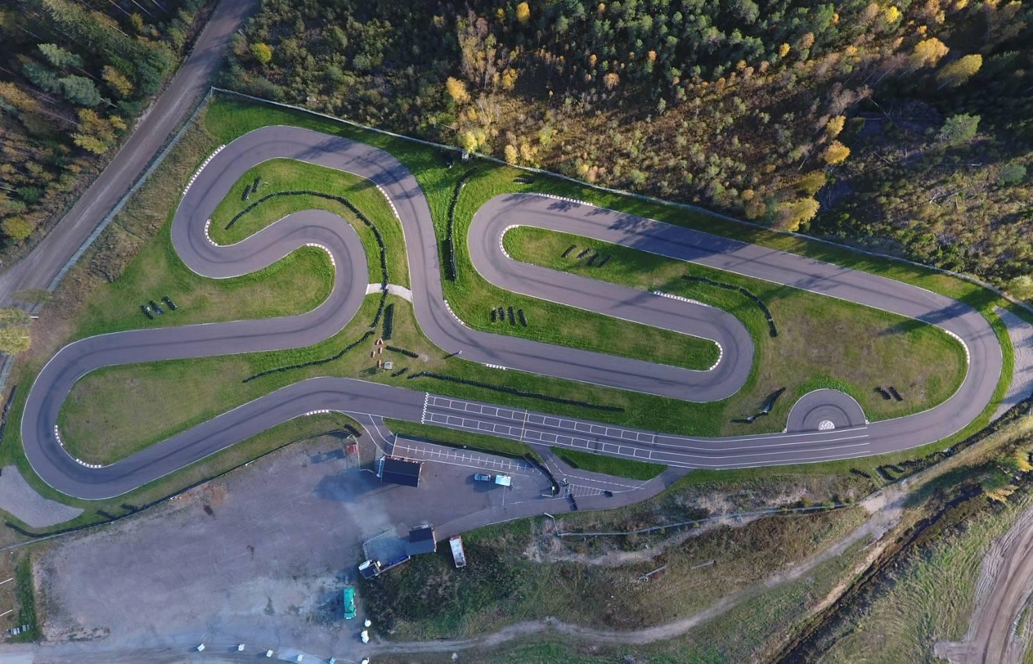 En drönarbild över en asfaltsbana vid ett skogsparti