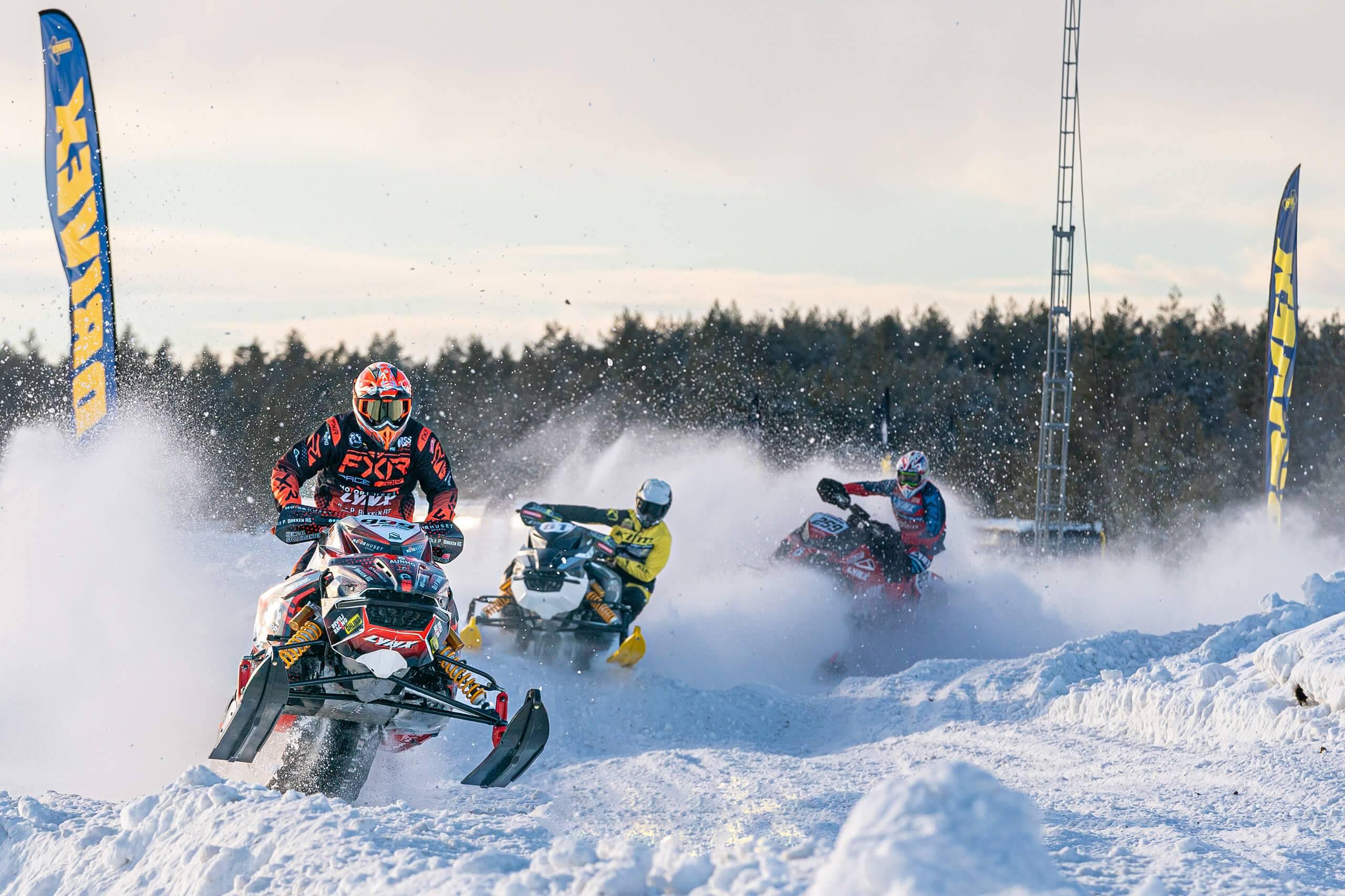 Tre förare i snöskoter som tävlar om att komma först ur en kurva