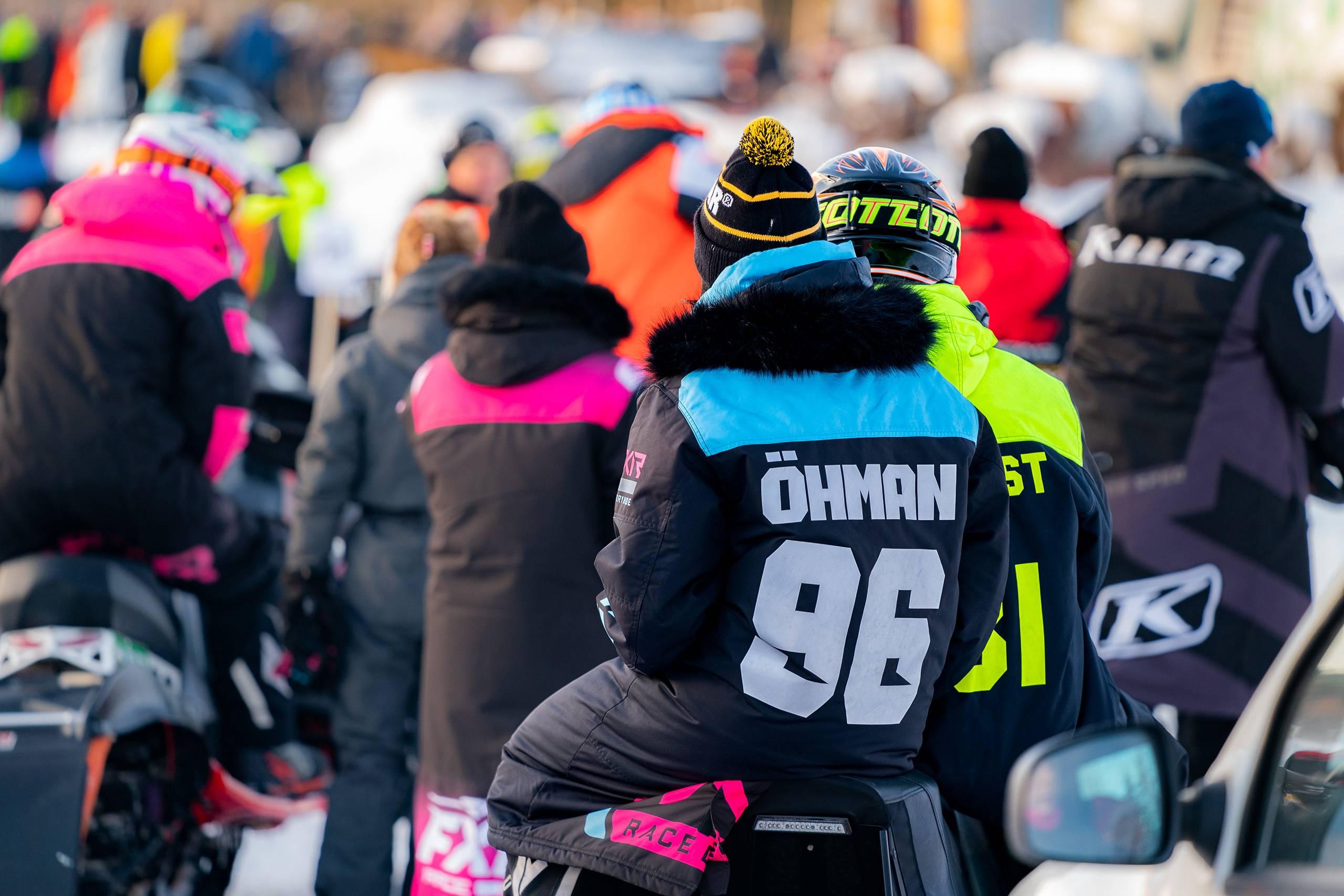 Flera snöskoterförare har samlats i en klunga för att lyssna på ett förarmöte.