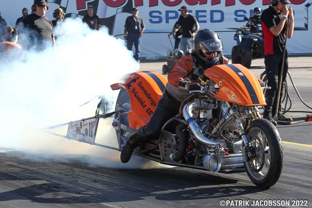 En förare på en dragracingbike med rök bolmande bakom sig