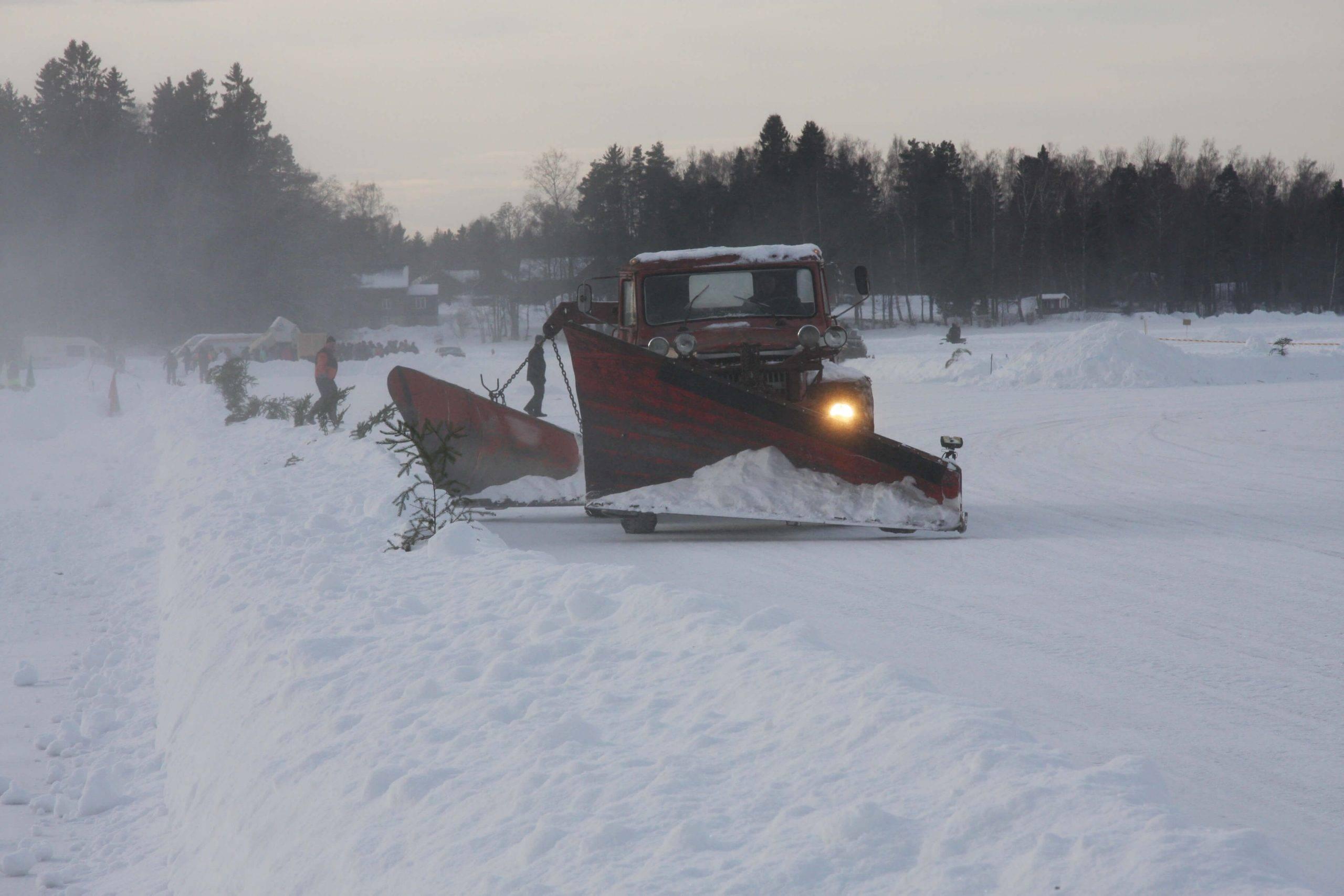 En röd plog som skottar en bana för sportgrenen isbana
