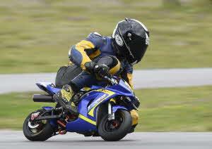 Förare sitter ihopkrupen på en blå och gul minimotohoj.