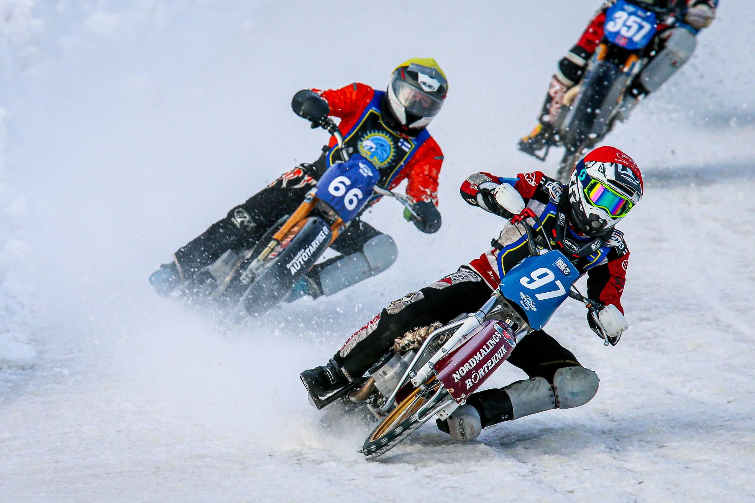 Två isracingförare i en kurva, isen skvätter upp.