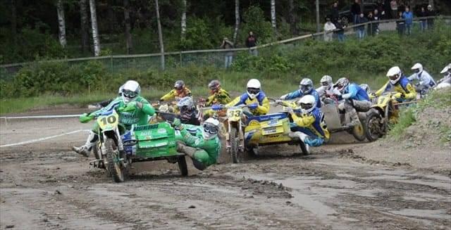 Flera förare och burkslavar slåss om förstaplatsen på en crossbana i sidvagnsmotocross.