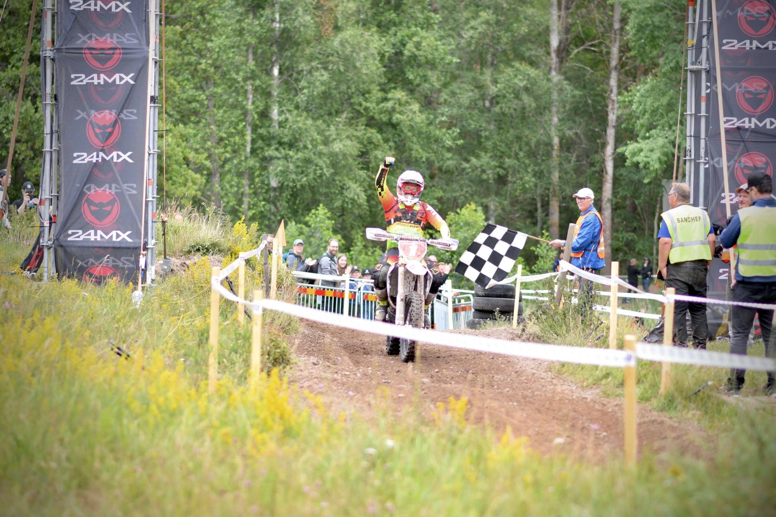 En enduroförare höjer näven i luften i en segergest vid målgång