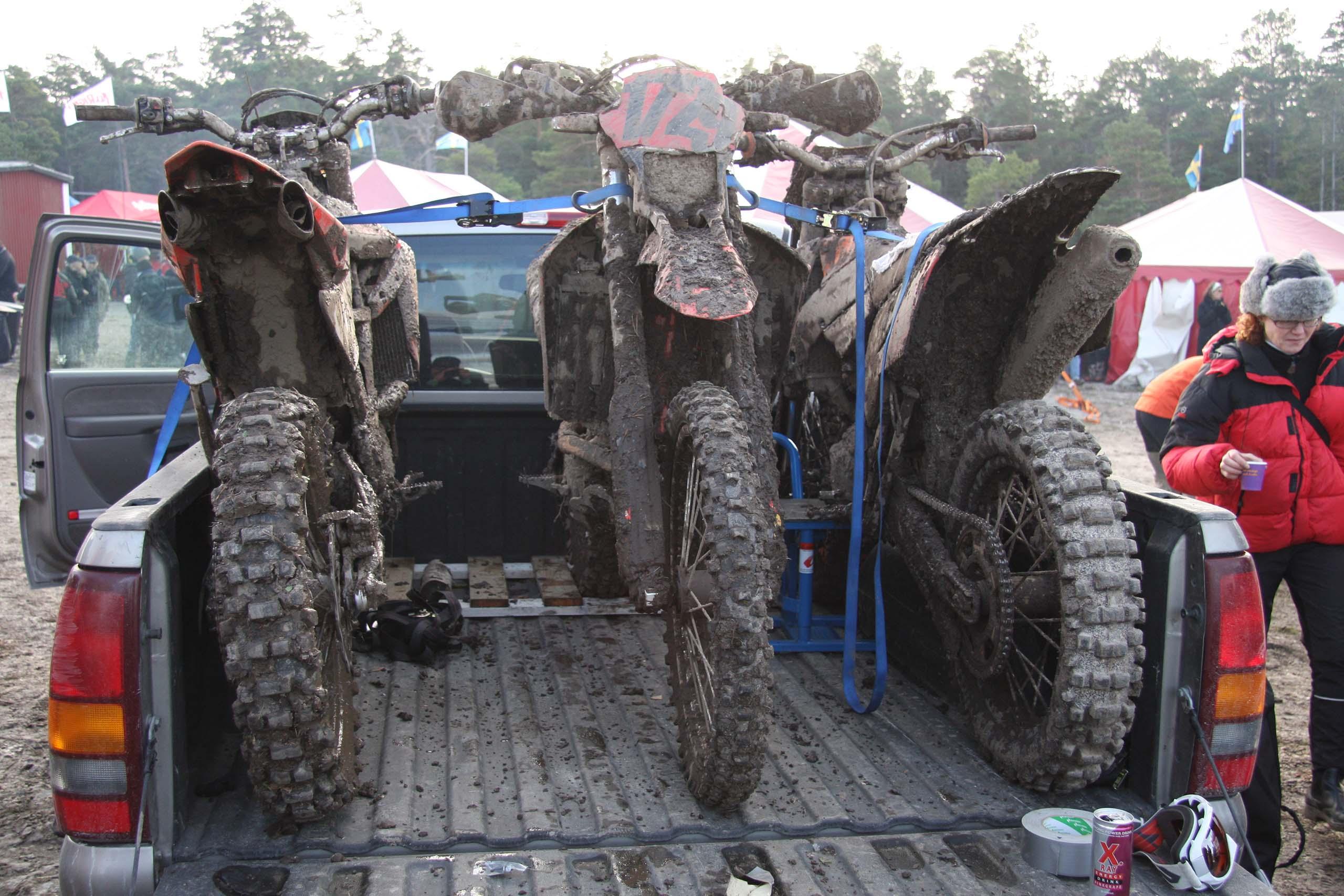 Tre leriga endurohojar står lastade och fastspända på ett bilflak.