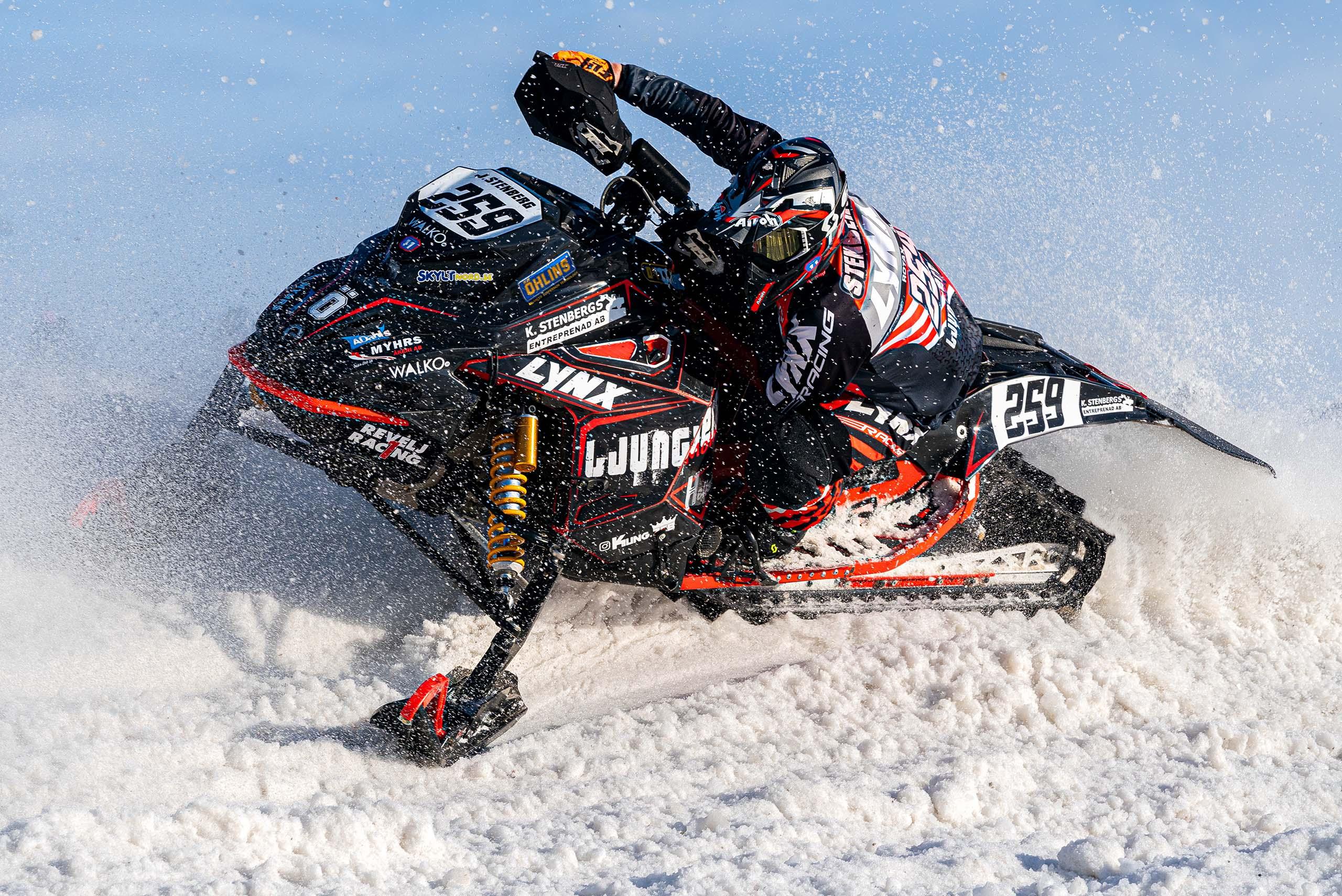 En snöskoterförare i full fart på sin skoter i en kurva.