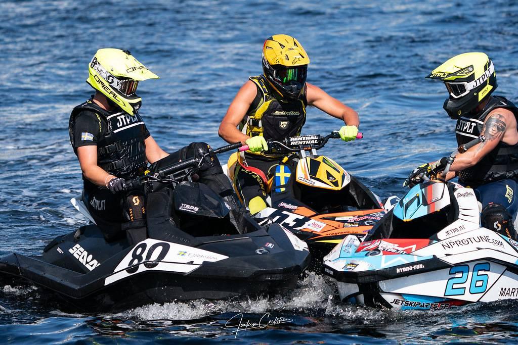 Tre förare på sina vattenskotrar med nosarna mot varandra i en grupp på vattnet